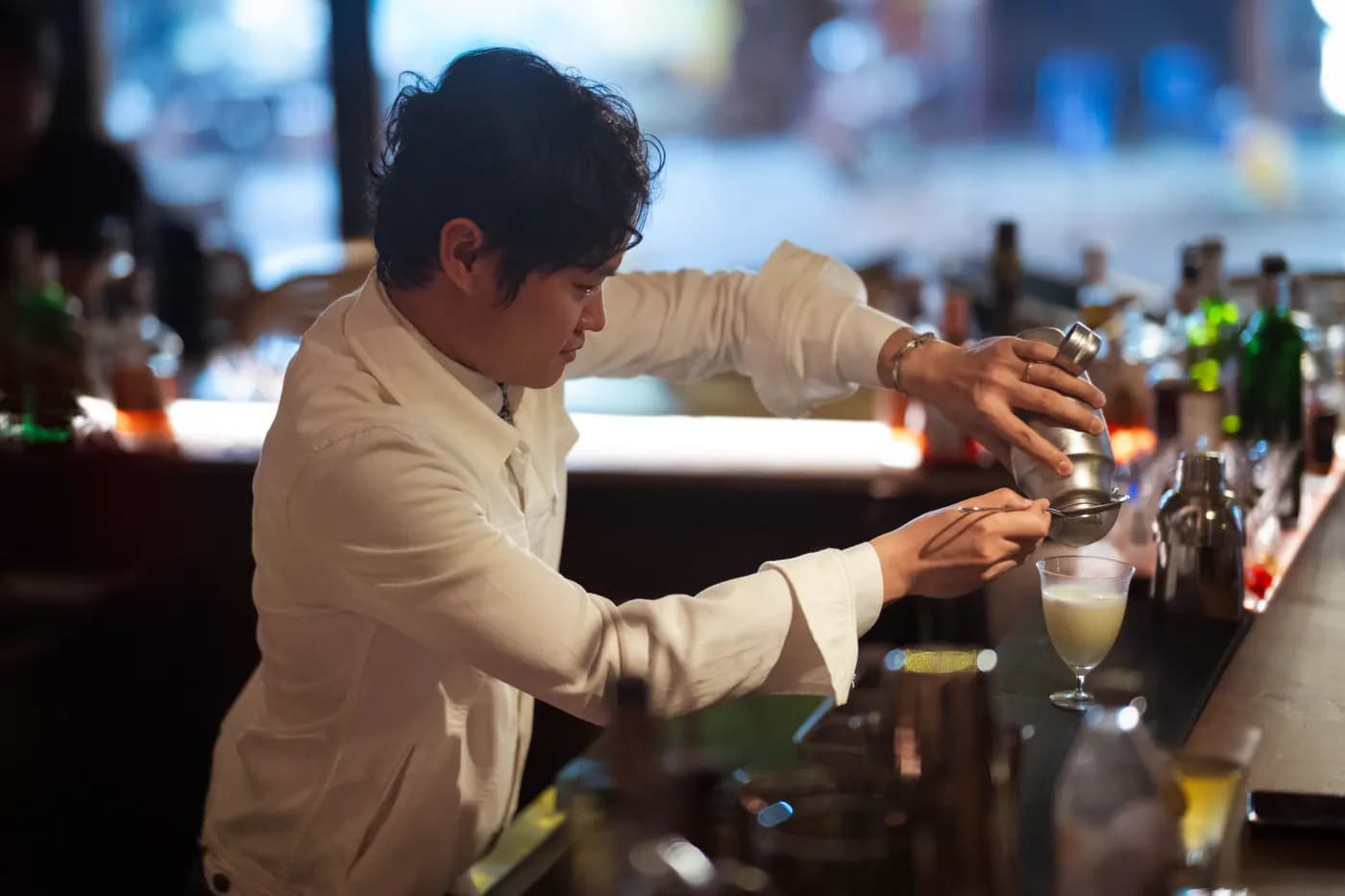 Bartender straining a cocktail